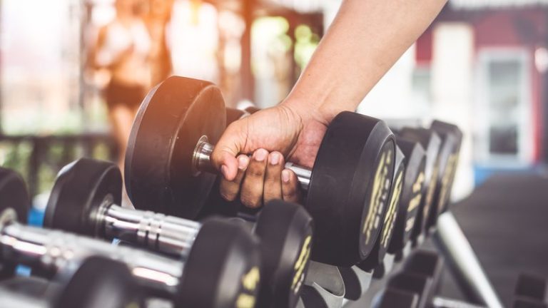 Hand pick up dumbbell on the rack in gym